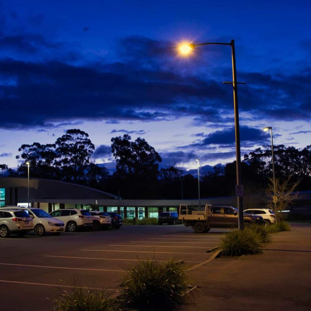 Twilight car park at Australian facility with streetlights.