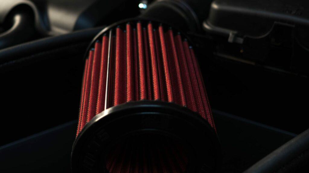Red performance air filter in car engine bay.