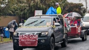 Rainy Christmas parade with decorated vehicle in Australia.