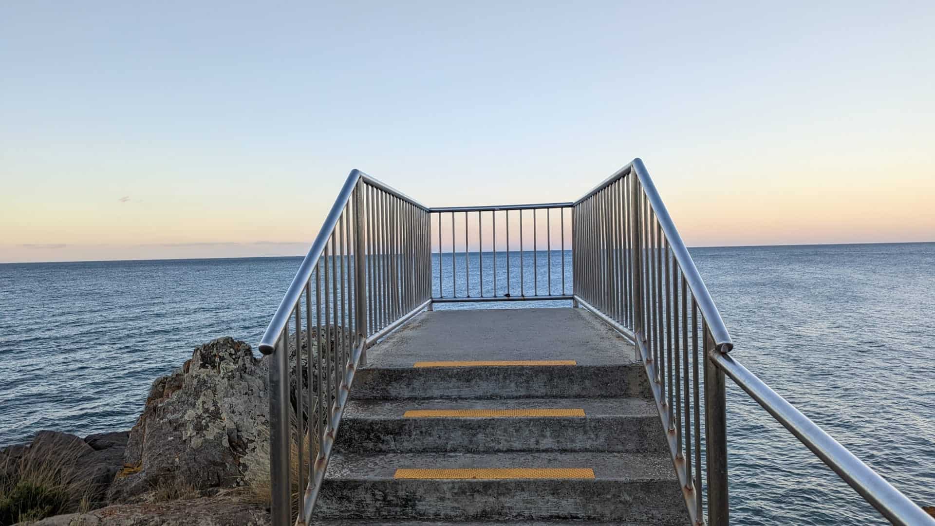 Ocean view from coastal staircase at sunset.