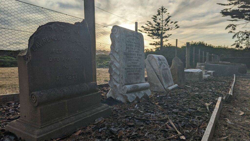 Old weathered gravestones in cemetery at dusk.