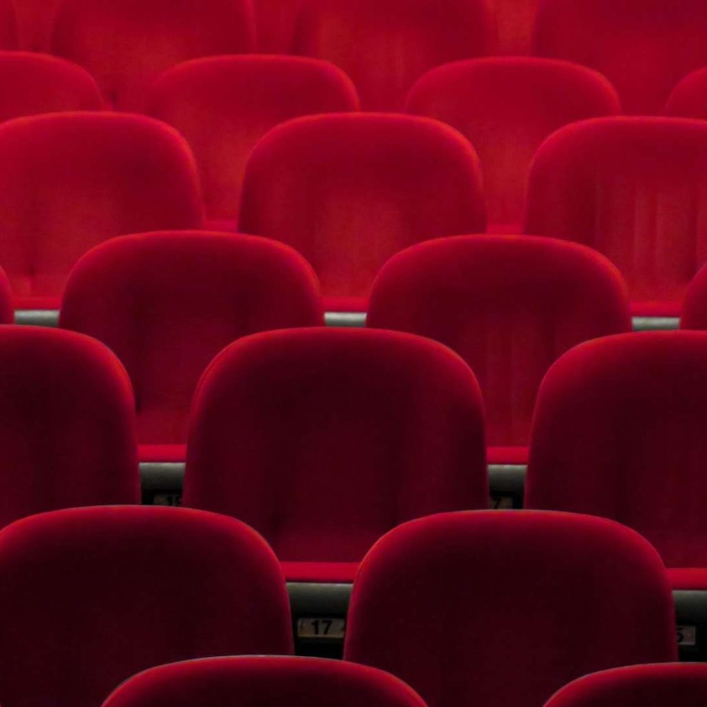 Empty red cinema seats in dim lighting.