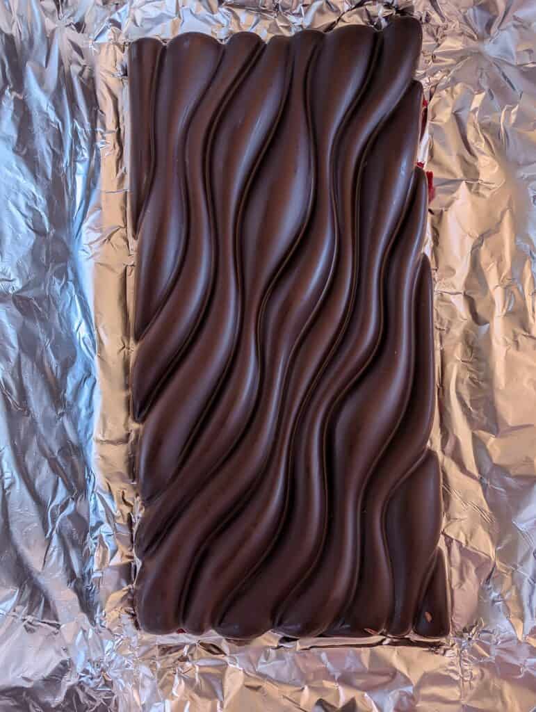 Large wavy dark chocolate bar on foil.